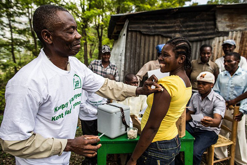 A health worker and other volunteers provide routine vaccines at the Community Center of Taifer to the population of a tiny Haitian mountain village. Gavi/Evelyn Hockstein